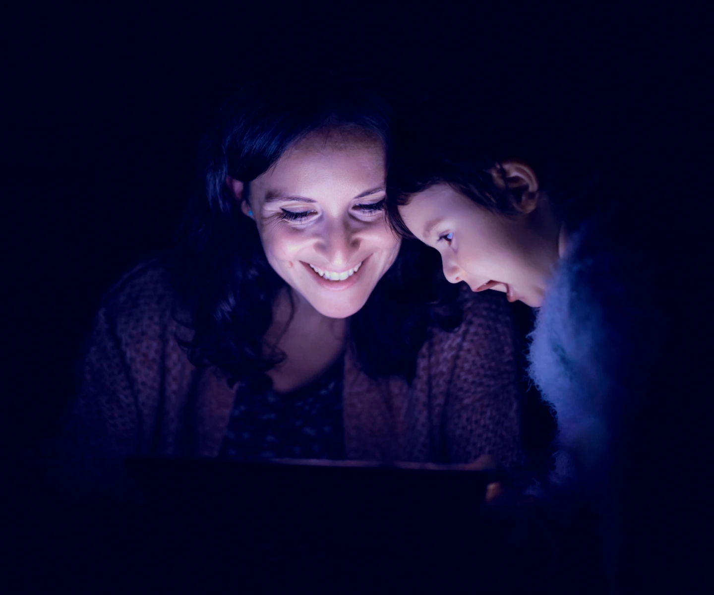 A mother and her child smiling as they look at a computer screen connected to Frontier internet, thanks to the discount programs available