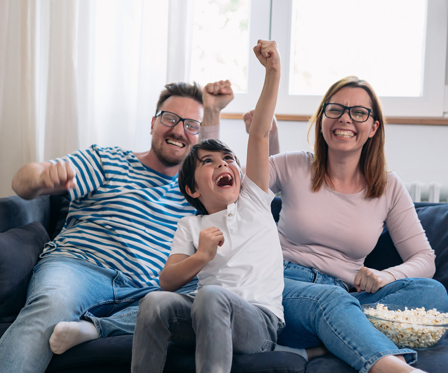 A family of three celebrating on the couch together