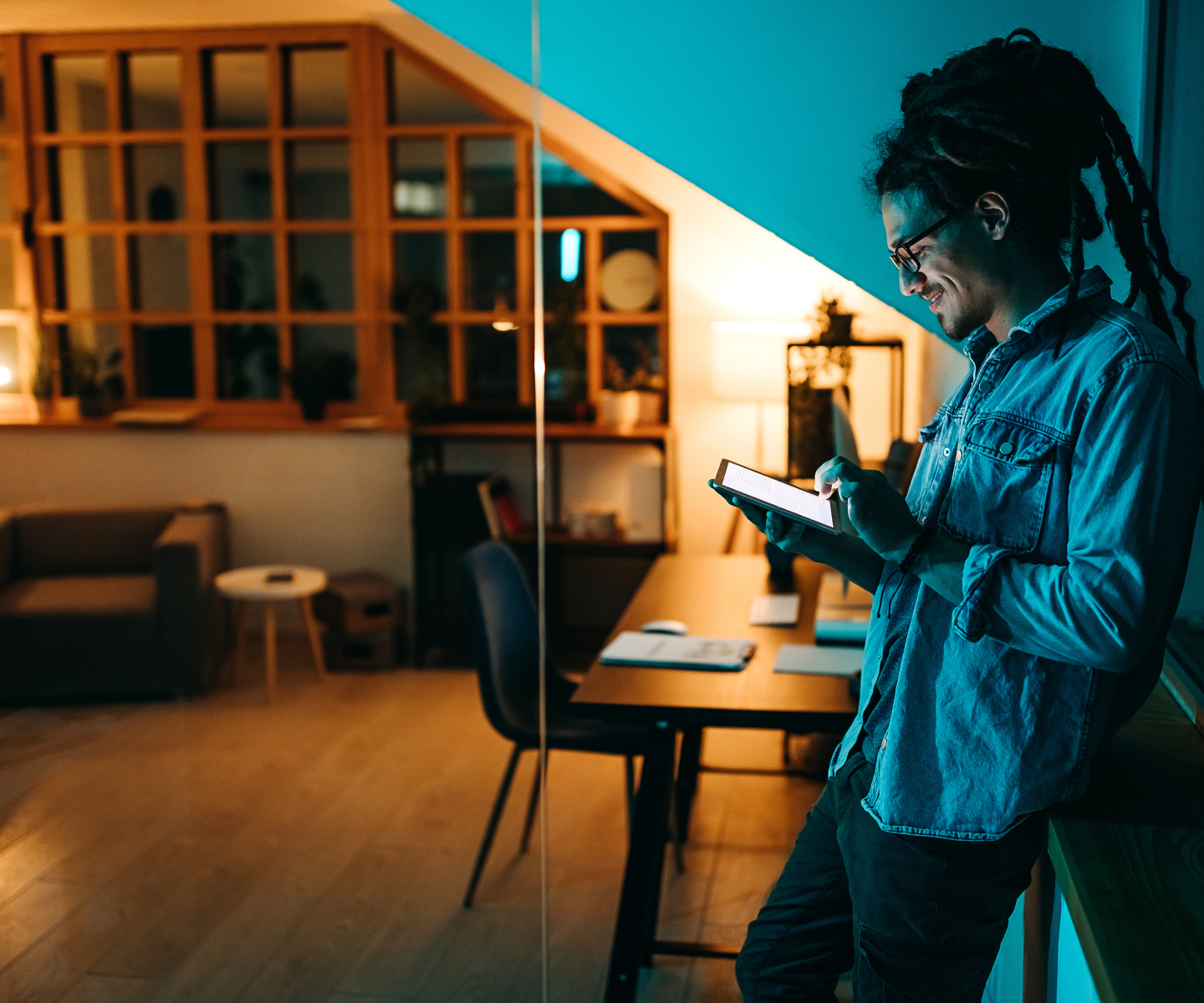 A man in a denim shirt using Frontier internet on his tablet in his living room